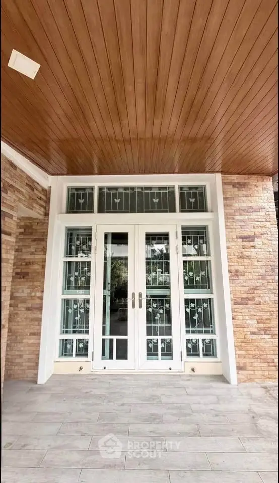Elegant entrance with wooden ceiling and glass-paneled doors in a modern home.