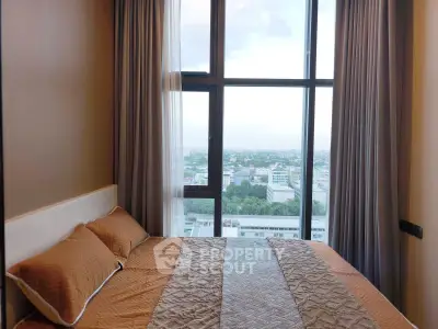 Luxurious bedroom with panoramic city view from large windows, featuring elegant bedding and curtains.
