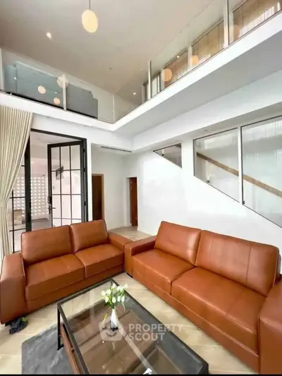 Spacious modern living room with high ceiling and elegant leather sofas