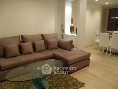 Modern living room with stylish brown sofa and glass coffee table in open layout apartment.