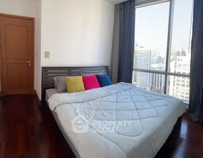 Luxurious bedroom with city view and modern decor in high-rise apartment.
