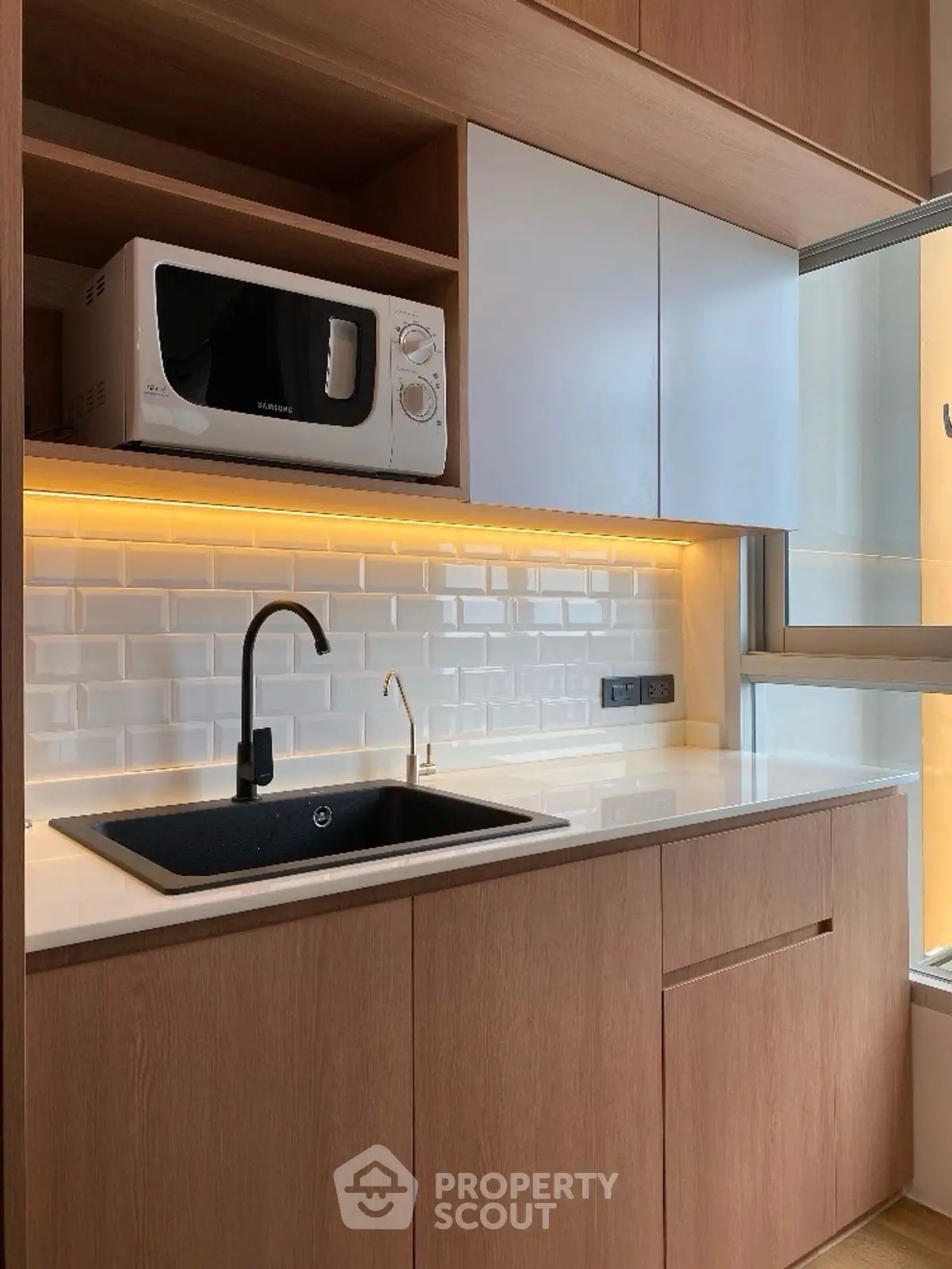 Modern kitchen with sleek cabinetry and built-in microwave, featuring under-cabinet lighting.