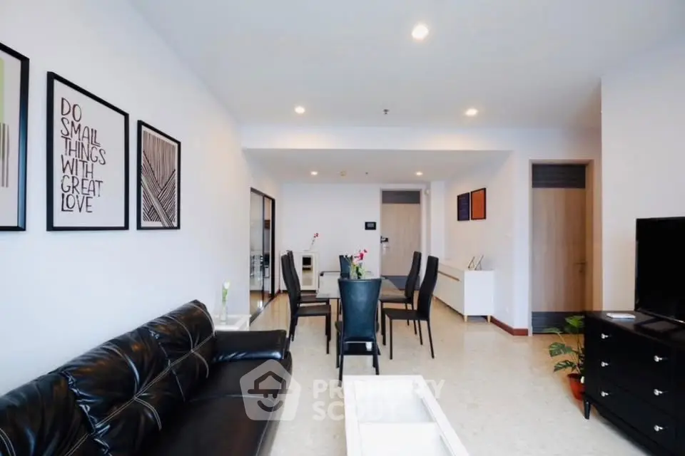 Spacious modern living room with sleek black leather sofa and elegant dining area.