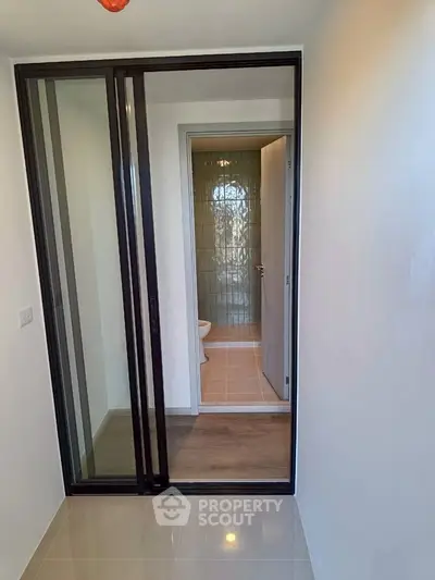 Modern bathroom entrance with sliding glass door and sleek tile flooring.