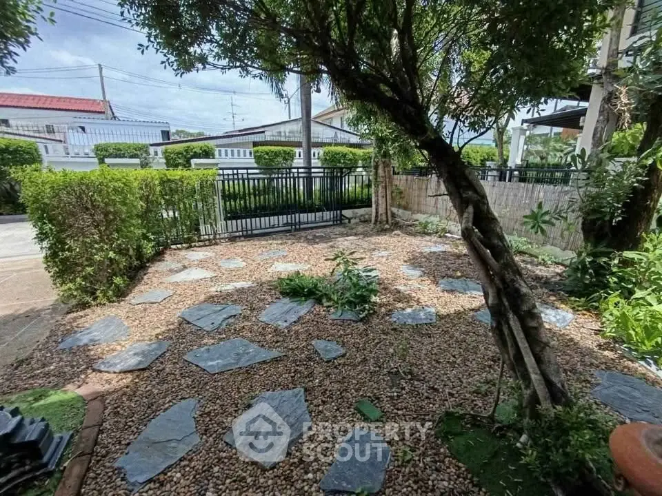 Charming garden with stone pathway and lush greenery in a serene residential area.
