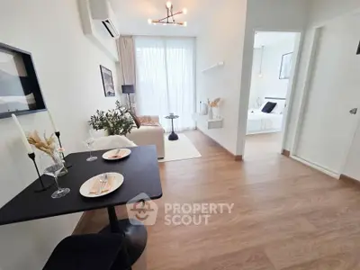 Modern open-plan living room with dining area and bedroom, featuring stylish decor and natural light.