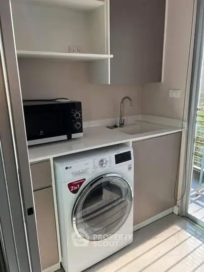 Modern compact kitchen with washing machine and microwave, ideal for urban living.