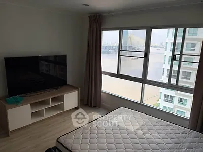 Bright bedroom with large window offering stunning river view and modern TV setup.