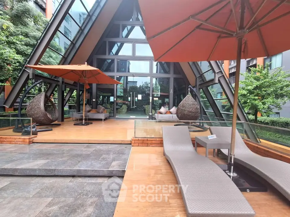 Luxurious modern building entrance with stylish outdoor seating and umbrellas