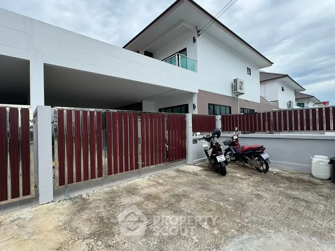 Modern two-story house with gated driveway and parked motorcycles
