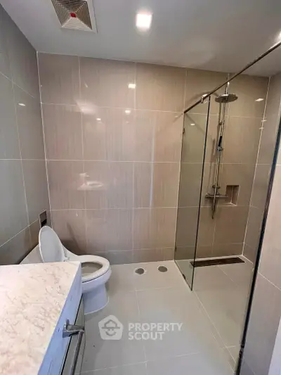 Modern bathroom with sleek glass shower and marble countertop in luxury apartment.