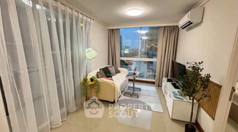 Cozy living room with modern decor and large window offering city views.