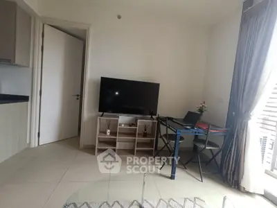 Modern living room with TV, glass table, and cozy seating area in a bright apartment.