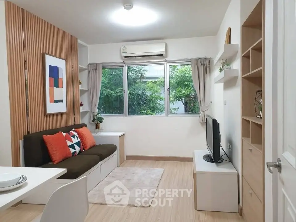 Modern living room with stylish decor and large window offering natural light.