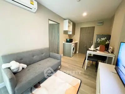 Modern living room with sofa, dining table, and in-unit washing machine in cozy apartment.