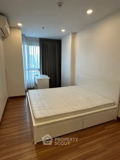 Spacious bedroom with modern design and large window offering natural light.