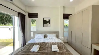 Spacious bedroom with large windows and modern decor, offering a serene view of the outdoors.