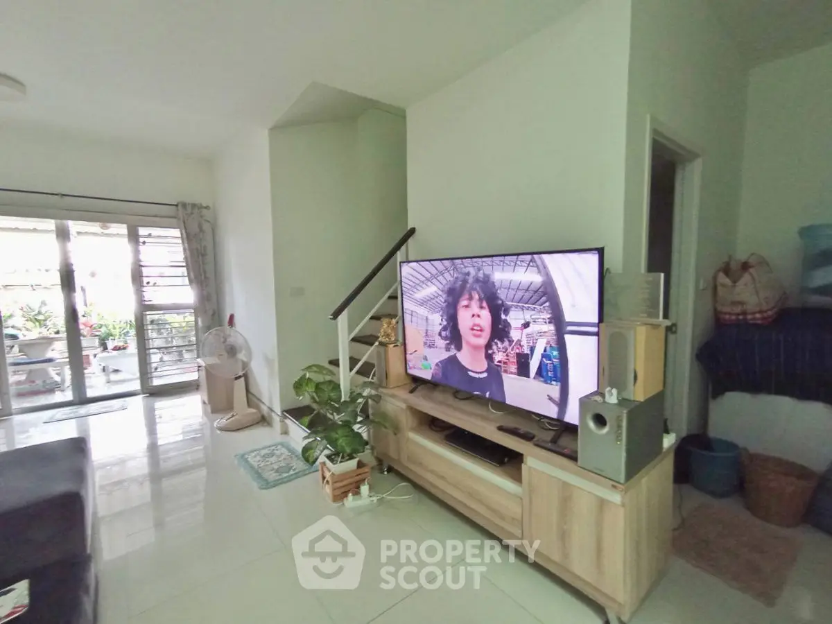 Spacious living room with modern TV setup and garden view balcony.