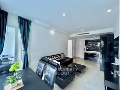 Modern living room with sleek black furniture and open kitchen layout in a stylish apartment.