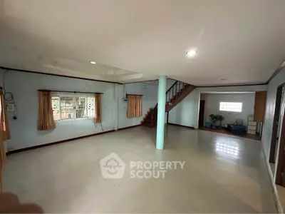 Spacious open-plan living area with staircase and large windows in a modern home.