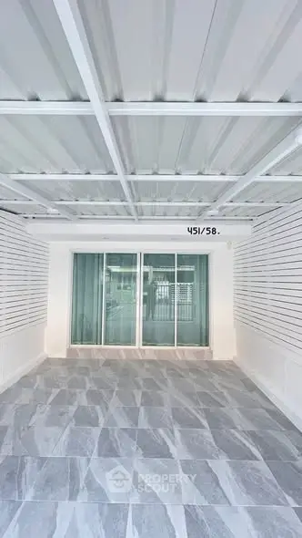 Modern covered parking area with sleek design and sliding glass doors.