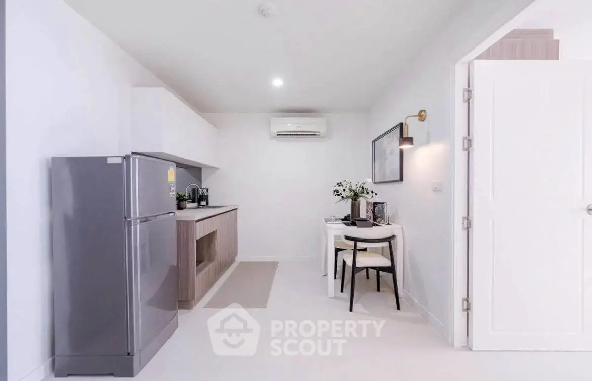 Modern kitchen with sleek appliances and cozy dining area in a bright, minimalist apartment.