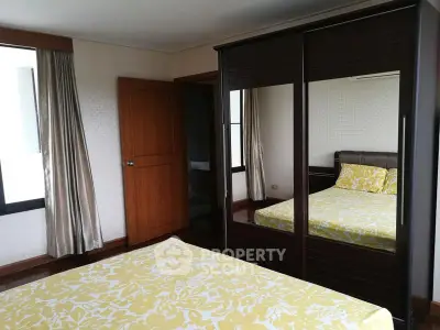 Spacious bedroom with mirrored wardrobe and stylish yellow bedding.