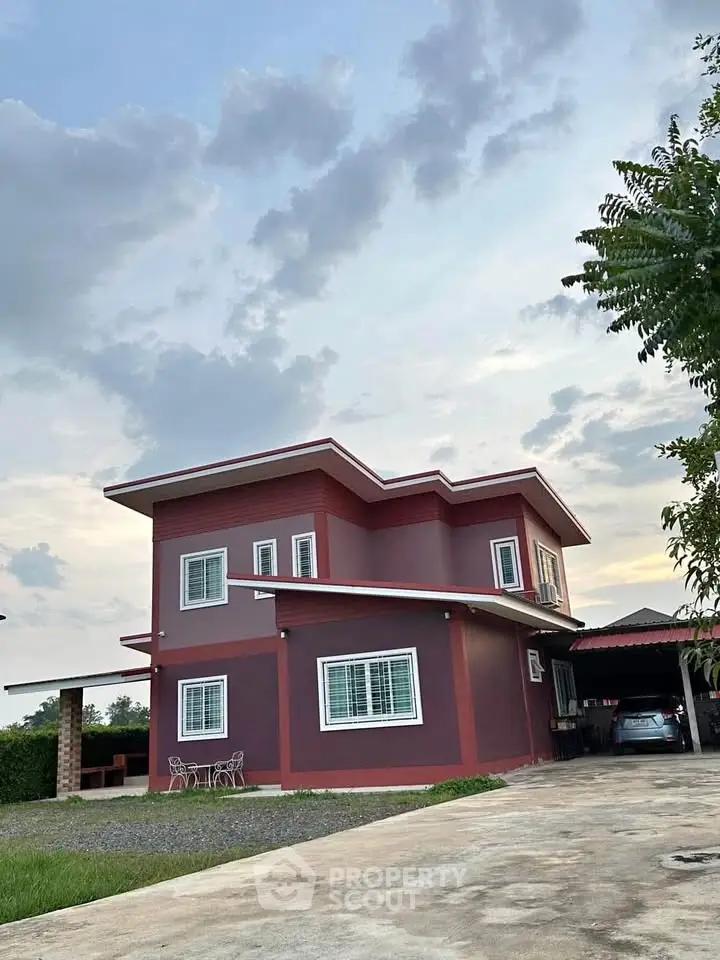 Charming two-story red house with spacious driveway and lush surroundings.