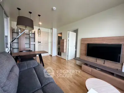 Modern living room with sleek furniture and wooden flooring, featuring a flat-screen TV and stylish lighting.