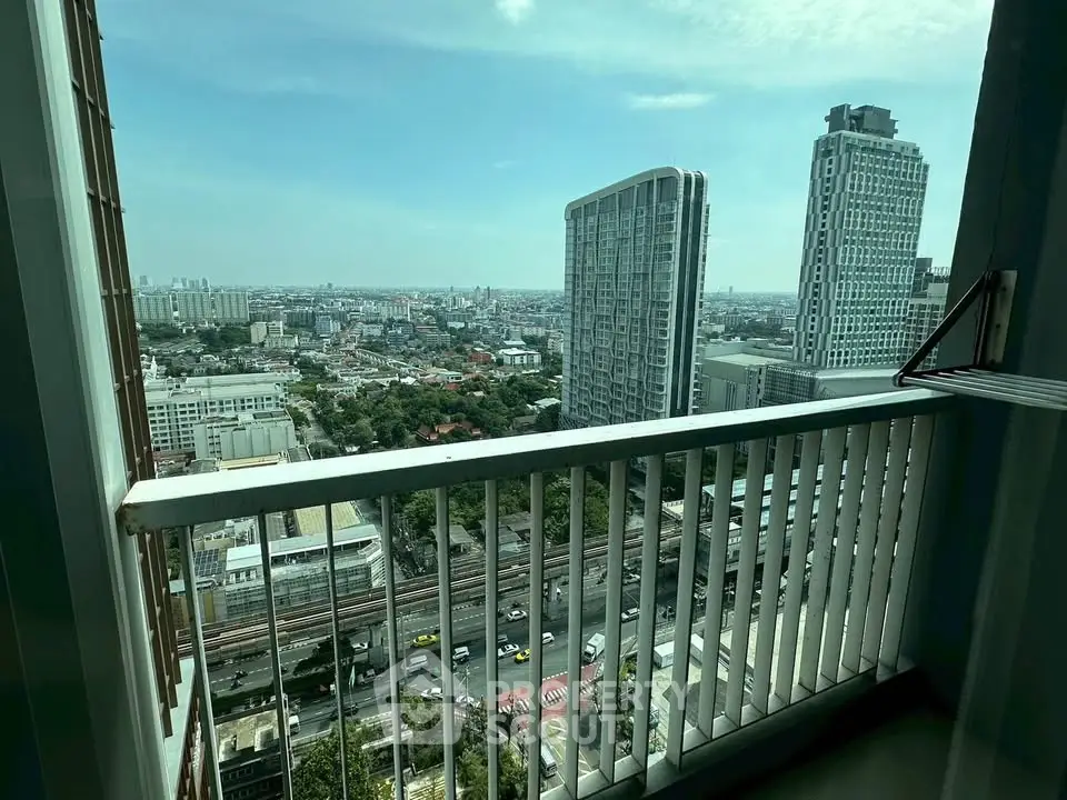 Stunning cityscape view from high-rise balcony with modern buildings and clear sky.