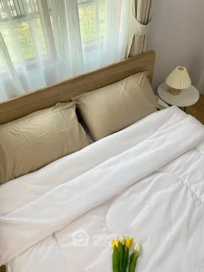 Cozy bedroom with elegant decor and natural light, featuring a stylish bed and soft linens.