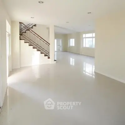 Spacious open-plan living area with elegant staircase and large windows