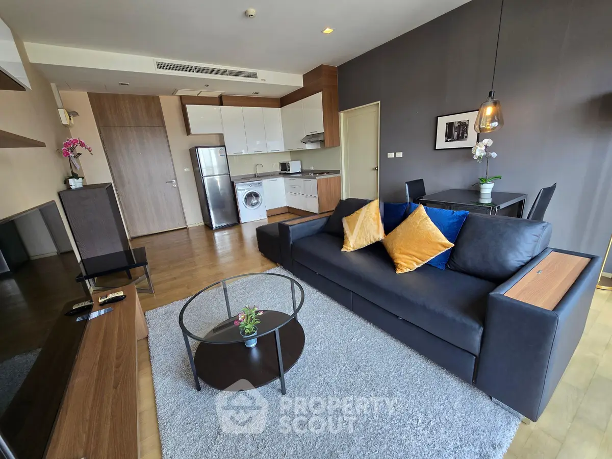 Modern living room with open kitchen, stylish decor, and cozy seating area in a contemporary apartment.