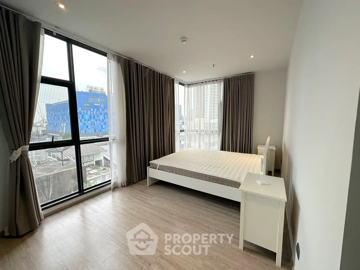 Spacious bedroom with large windows and modern decor in urban apartment