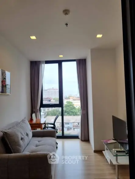 Modern living room with large window and city view, featuring a cozy sofa and sleek decor.
