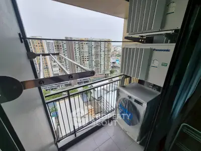Compact balcony with air conditioning units overlooking urban skyline.