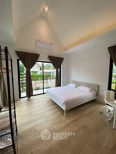 Spacious bedroom with large windows and modern decor in a bright, airy home.
