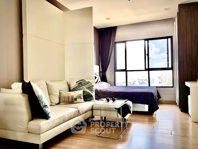 Modern studio apartment with cozy living area and large window view.