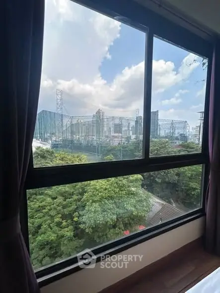 Stunning cityscape view from a high-rise apartment window, showcasing lush greenery and urban skyline.