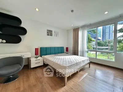 Spacious bedroom with modern decor and large window offering a scenic view, perfect for urban living.