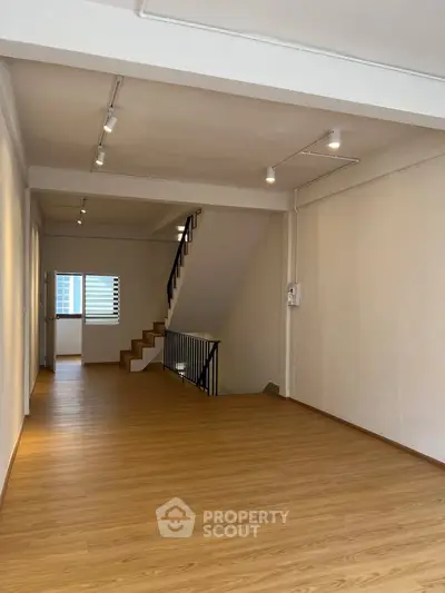 Spacious open-plan living area with wooden flooring and staircase, ideal for modern living.