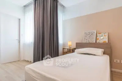 Cozy bedroom with modern decor and natural light, featuring a single bed and stylish artwork.
