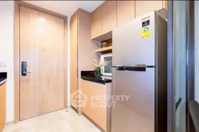Modern kitchen with sleek fridge and wooden cabinetry in a stylish apartment.