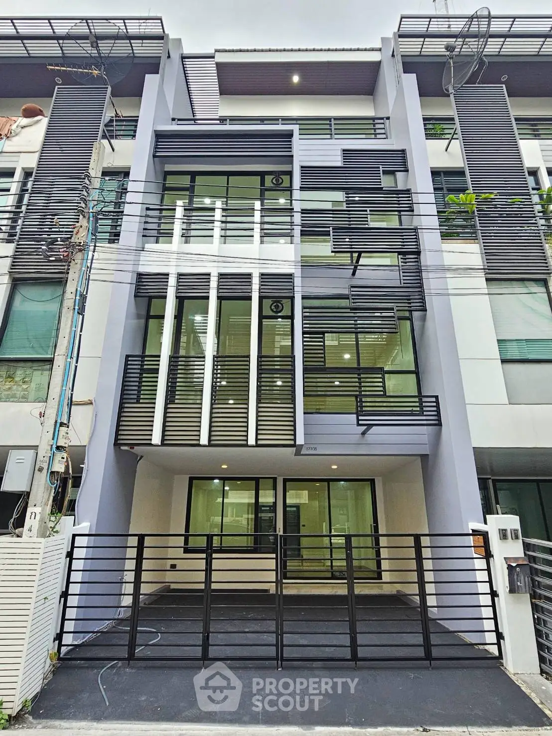 Modern multi-story townhouse with sleek facade and large windows in urban setting.