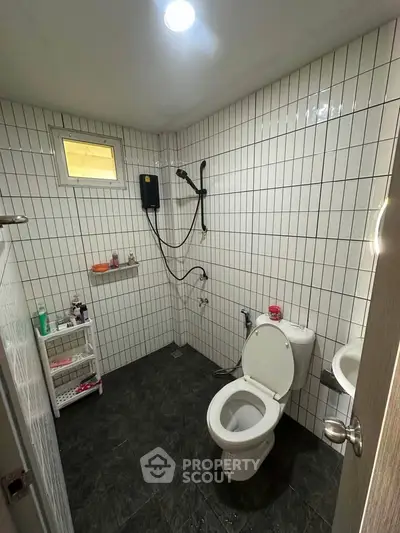 Modern bathroom with tiled walls and floor, featuring a shower and toilet in a compact layout.