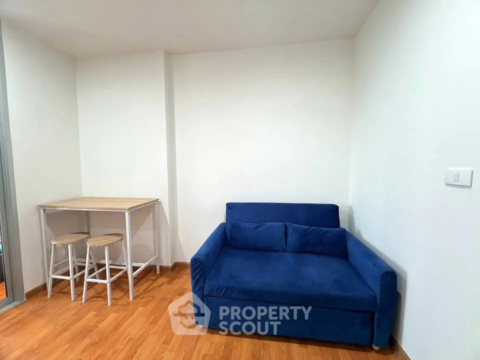 Cozy living room with blue sofa and wooden floor, perfect for relaxation.