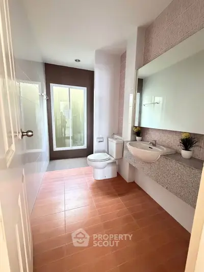 Spacious modern bathroom with elegant fixtures and large mirror, featuring a sleek design and natural light.