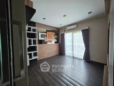 Modern living room with dark wood flooring and large windows for natural light.