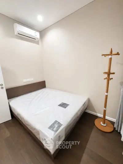 Modern bedroom with air conditioning and wooden flooring, featuring a minimalist design and cozy atmosphere.