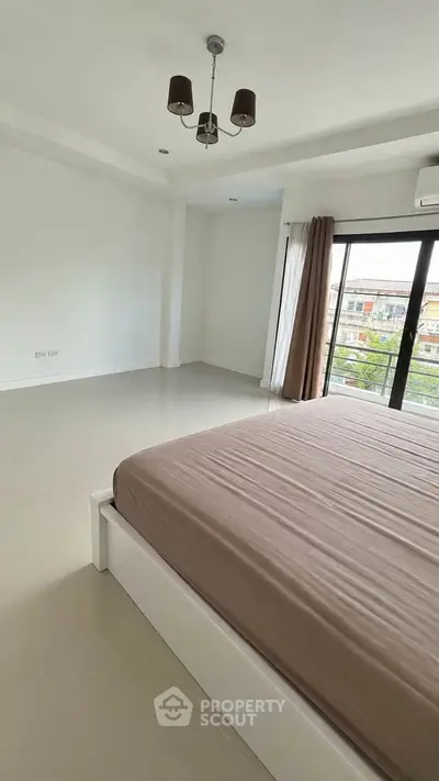 Spacious bedroom with large windows and modern decor in a bright apartment.